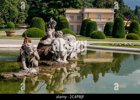 Como, Lombardei, Italien. Villa Olmo (1782), eine wichtige neoklassizistische Villa in Como, entworfen von dem Architekten Simone Cantoni, während der Restaurierungsarbeiten. Der monumentale Brunnen vor der Villa Olmo zeigt ein Seeungeheuer, das mit drei Cherubim kämpft; er ist das Werk des Mailänder Bildhauers Gerolamo Oldofredi (Mailand 1840-1905) und wurde von den Herzögen Visconti di Modrone aufgestellt. Stockfoto