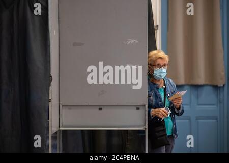 (200628) -- PARIS, 28. Juni 2020 (Xinhua) -- EINE Frau mit Schutzmaske bereitet sich auf die Wahl in einem Wahllokal während der zweiten Runde der Kommunalwahlen in Paris, Frankreich, am 28. Juni 2020 vor. Da sich die COVID-19-Epidemie in Frankreich immer besser entwickelt, werden am Sonntag rund 16.5 Millionen Wähler aufgerufen, im Rahmen eines strengen Gesundheitsprotokolls bei der zweiten Runde der Kommunalwahlen ihre Stimme zu geben. Die zweite Runde der Bürgermeisterwahlen war ursprünglich für März 22 geplant, aber die Verschlimmerung der Coronavirus-Ausbrüche und die Sperrung des Virus hatten die französische Regierung gezwungen, sie zu verschieben. (Foto von Aurel Stockfoto