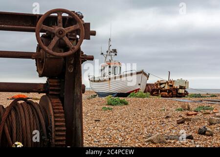 Fischerboot und verlassene und rostende Windenmaschinen am Kiesstrand in Dungeness, Kent Stockfoto
