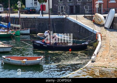 Zwei ältere Männer, die in Castletown, Harbour, Isle of man, an der Absailung von Segeln auf einem hölzernen Segelboot arbeiten Stockfoto