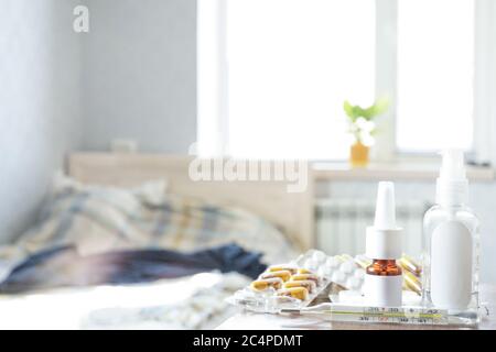 Thermometer, Nasentropfen und Pillen sind auf dem Nachttisch im Zimmer, Medikamente zu Hause. Stockfoto