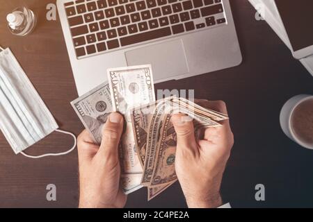 Geschäftsmann, der an der Büroschreibtisch Bargeld in us-Dollar-Papier zählt, von oben aus die männlichen Hände mit Geld betrachtet Stockfoto