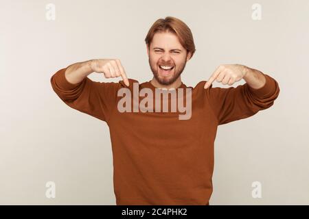 Achtung Werbung unten! Porträt von begeisterten begeistert gut aussehenden bärtigen Mann zeigt nach unten und lächelt auf die Kamera, zeigt Platz für Idee pres Stockfoto