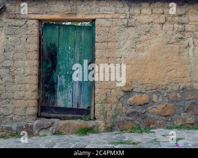 Eine sehr alte grüne Holztür in Ruinen in einer Straße in der Kolonialstadt Villa de Leyva in den Andenbergen von Zentral-Kolumbien. Stockfoto