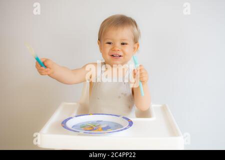 Blonde Baby sitzt in den Hochstuhl und lächelt Stockfoto