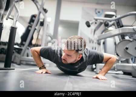 Muskulösen attraktiven Kerl tun Liegestütze im Fitnessstudio Stockfoto
