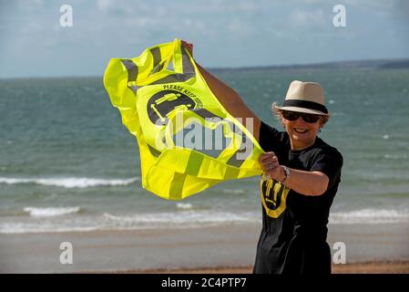 Southsea, Hampshire, England, Großbritannien. Juni 2020. Frau trägt soziale distanzierende T-Shirt und halten Sie Ihre Distanz his vis Weste an einem windigen Tag am Strand ein Stockfoto