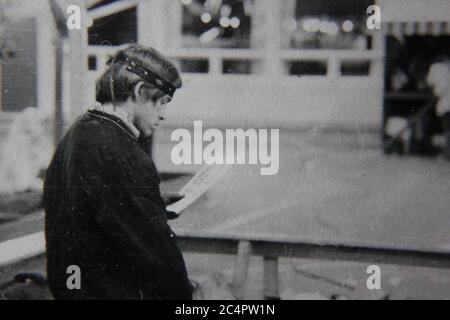 Feine 70er Jahre Vintage schwarz-weiß Lifestyle Fotografie von einem Ticketverkäufer an der Karnevalsmanning einen Kiosk. Stockfoto