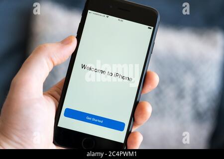 Eine Männerhand mit einem iPhone 7-Handy, die eine Nahaufnahme des Startbildschirms „Willkommen beim iPhone“ mit einer „erste Schritte“-Einführungsschaltfläche zeigt, Großbritannien Stockfoto