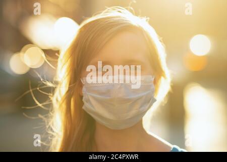 Leben während einer Coronavirus-Pandemie. Portrait of modern girl in blau insgesamt mit medizinischen Maske im Freien in der Stadt. Stockfoto