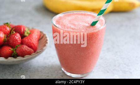 Erdbeer-Smoothie im Glas mit grünem Trinkhalm. Frischer, roher Erdbeer-Smoothie oder Sommercocktail Stockfoto
