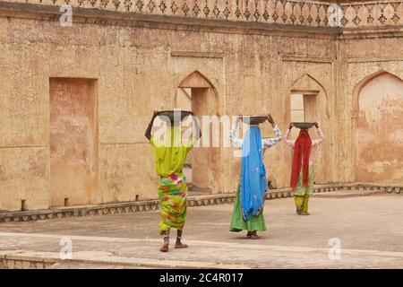 Weibliche Arbeiter Transport von Wasser und Gips in Schalen auf dem Kopf während der Restaurierung eines Palastes in Amber Fort in Jaipur, Indien. Stockfoto