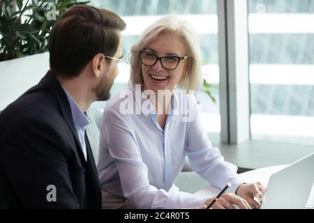 Ältere Geschäftsfrau sitzt neben Untergebenen Stockfoto