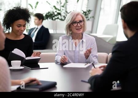 Mentorin mittleren Alters, die ein Ausbildungstreffen mit jungen Fachleuten durchführt Stockfoto