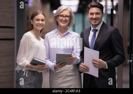 Lächelnde, selbstbewusste Geschäftsleute stehen im Büro zusammen Stockfoto