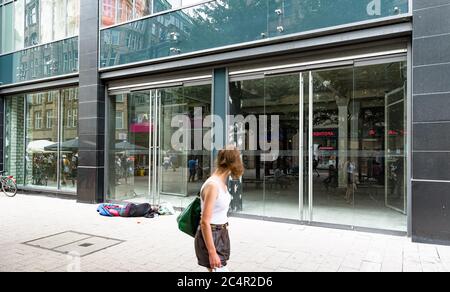 Hamburg, Deutschland. Juni 2020. Eine Frau geht an einem leeren Laden in der Spitalerstraße vorbei, vor dem ein Mann in einem Schlafsack liegt. Quelle: Markus Scholz/dpa/Alamy Live News Stockfoto