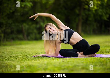 Stretching Frau in Outdoor-Sport-Übung. Lächelnd glücklich Yoga zu tun streckt nach dem Laufen. Stockfoto