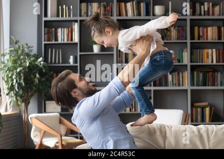 Glücklicher junger Vater hält kleine Tochter vorgeblich fliegen Stockfoto