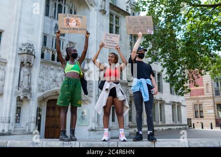 Drei Demonstranten stehen an einer Wand und halten während einer Demonstration von Black Lives Matter Schilder hoch, Parliament Square, London, 20. Juni 2020 Stockfoto