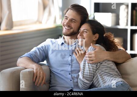 Lächelnd verträumte Frau und Mann umarmen, entspannen auf gemütliche Couch Stockfoto