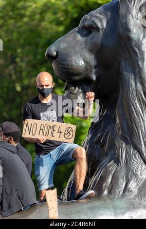 Ein Mann hebt seine Faust neben einer Löwenskulptur während einer Demonstration der Schwarzen Leben, Trafalgar Square, London, 20. Juni 2020 Stockfoto