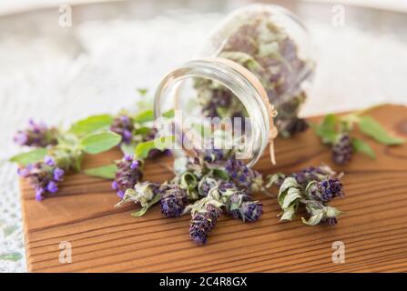 Zusammensetzung von Prunella vulgaris (bekannt als gemeinsame selbst-heilen, heilen-alle, Wundwort trockenen Kräuterteepulver mit frischen Blumen auf natürlichem Holz. Stockfoto