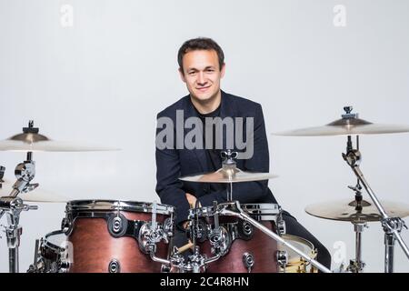 Junger Drummer hinter Drum Set und spielt die Drums im Studio lächelnd Stockfoto