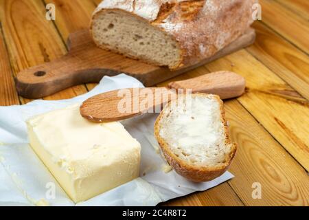 Leckeres frisches Brot und Butter auf einem Holztisch. Brot in der Küche. Dunkler Hintergrund. Stockfoto