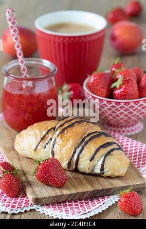 Tischdekoration mit Croissant, Erdbeermarmelade und einer Tasse Kaffee Stockfoto