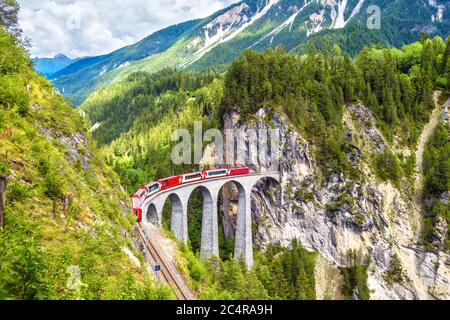 Landwasser Viadukt im Sommer, Filisur, Schweiz. Es ist Wahrzeichen der Schweizer Alpen. Schöne alpine Landschaft. Roter Zug von Bernina Express auf der Brid Stockfoto