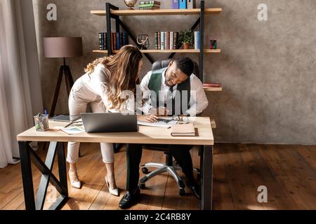 Glückliche junge Frau und schöner Mann arbeiten zusammen im Büro Stockfoto