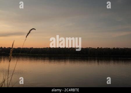 Schöner Sonnenuntergang am Ufer eines großen Flusses Stockfoto