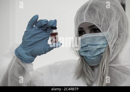 Forscher in schützende Schutzanzug ein Reagenzglas im chemischen Labor untersuchen. Stockfoto