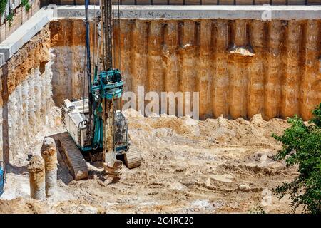 Ein Schwerbagger in Verbindung mit einem Bohrgerät stärkt die Fundamente des zukünftigen Hochhauses. Stockfoto