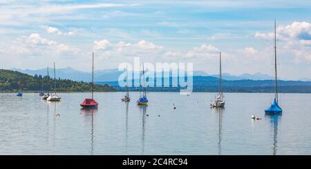 Panorama mit bunten Segelbooten, die am Ammersee ankern. Alpen am Horizont. Stockfoto