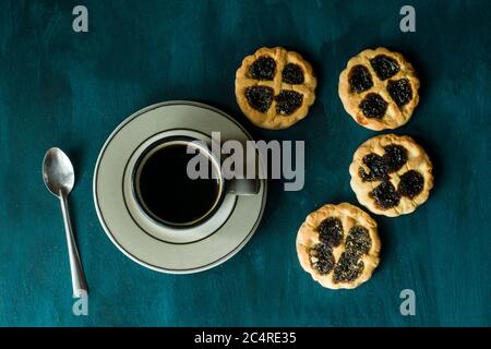 Ein paar Kekse und eine Tasse Kaffee auf einem blauen Tisch. Stockfoto