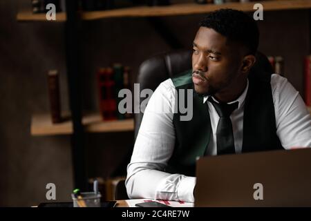 Schöner afrikanischer Geschäftsmann, der mit einem Laptop im modernen Büro arbeitet Stockfoto