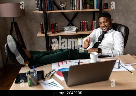 Schöner afrikanischer Geschäftsmann, der mit einem Laptop im modernen Büro arbeitet Stockfoto