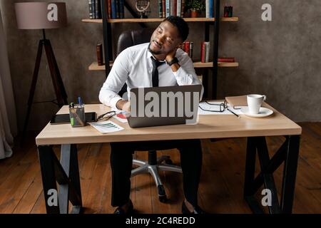 Schöner afrikanischer Geschäftsmann müde nach der Arbeit in modernen Büro Stockfoto