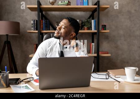 Schöner afrikanischer Geschäftsmann müde nach der Arbeit in modernen Büro Stockfoto