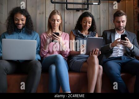 Vier multiethnische Menschen mit verschiedenen modernen elektronischen Geräten Stockfoto