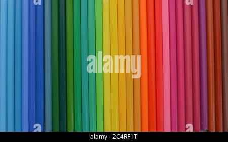 Farbige Holzstifte sind in einer Reihe angeordnet. Eine Palette von Buntstiften. Nahaufnahme, auf Holzhintergrund Stockfoto