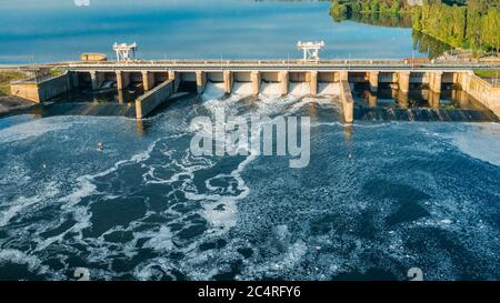 Damm mit fließendem Wasser durch Tore. Wasserkraftwerk, Luftaufnahme von oben. Stockfoto