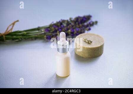 Kosmetische natürliche Lavendel Seife und Serum oder ätherisches Öl auf hellgrauem Hintergrund. Aromatherapie, Spa-Konzept. Stockfoto