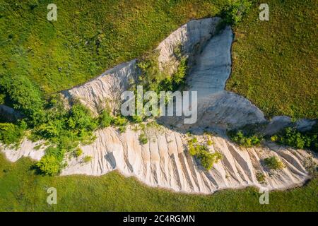 Kreidespalte oder Schlucht zwischen grünen Gras Wiese Hügel, Luftaufnahme von oben, abstrakte Natur Hintergrund. Stockfoto