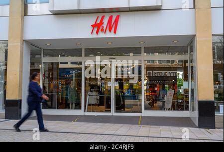 Bromley (Großraum London), Kent, Großbritannien. H&M-Geschäft in der Bromley High Street mit einem verschwommenen Fußgänger vorbei. H&M Shop mit Reflexionen in den Fenstern. Stockfoto