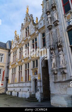 Brügge, Belgien 02/29/2020. Burgplatz bei bewölktem Tag, altes Gebäude mit Fahnen und goldenen Ornamenten auf dem Dach. Stockfoto