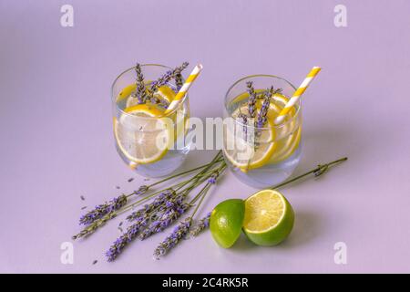 Gläser mit Lavendellimonade auf hellem Fliedertisch, Blumen und Limettenscheiben. Nahaufnahme Stockfoto
