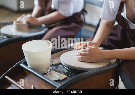 Die Herstellung von Keramik. Zwei Frau bereiten Ton für die Arbeit auf Töpferscheibe. Nahaufnahme der Hände. Stockfoto