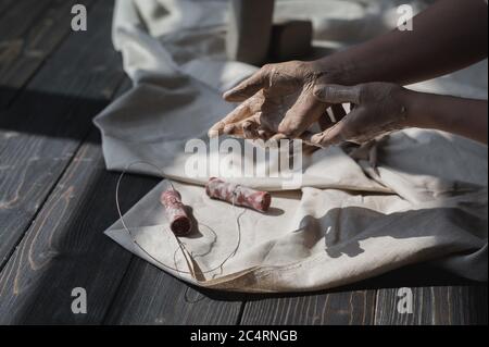 Die in Ton gefärbten Hände gehen, um Schnitt Werkzeug aus Holztisch, Kunsttherapie Konzept zu nehmen Stockfoto